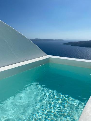 a pool of blue water next to the ocean at Panorama Suites in Fira