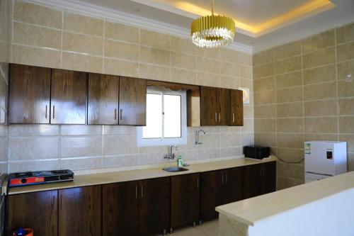 a kitchen with wooden cabinets and a sink and a window at Al Chaffa Chalets in Ţurayf