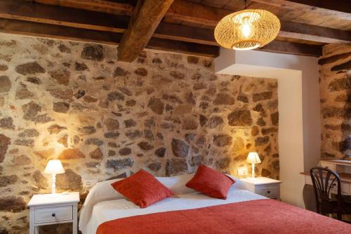 a bedroom with a bed and a stone wall at Casas del Castillo, 1 in Ávila