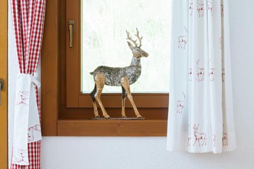 a statue of a deer standing on a window sill at Alpenhotel Wanderniki in Liesing