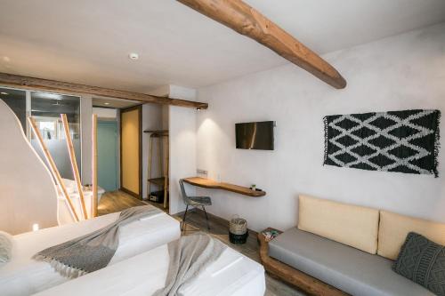 a bedroom with a bed and a couch and a tv at Sunrise Village Hotel Apartments in Skopelos Town