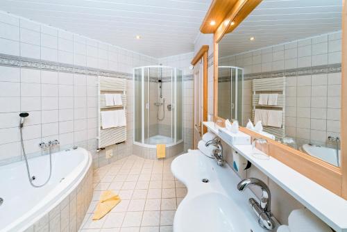 a bathroom with a tub and a sink and a bath tub at Alpenhotel Wanderniki in Liesing