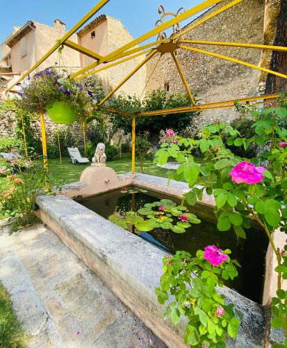 a garden with a pond with flowers and a fountain at Les Arcades Le Lion D'or in Buis-les-Baronnies
