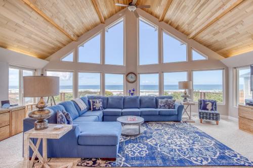 a living room with a blue couch and windows at Neptune Lookout in Lincoln City