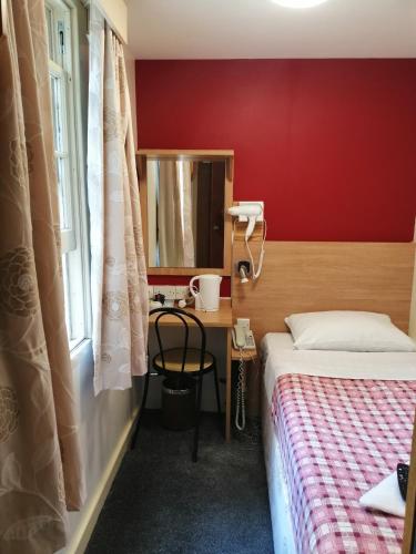a bedroom with a bed and a desk with a mirror at Colliers Hotel in London