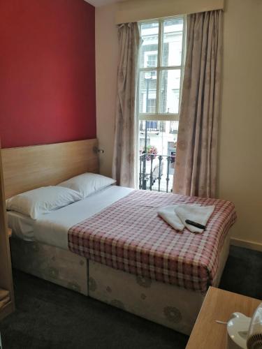 a bed sitting in a room with a window at Colliers Hotel in London