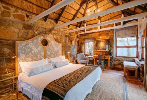 a bedroom with a bed in a room with a stone wall at Moontide Riverside Lodge in Wilderness
