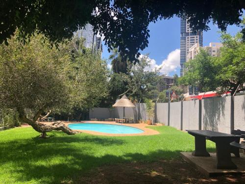 una piscina en un patio con una mesa de picnic y un árbol en Sandton Luxury Living at 102 Kambula, en Johannesburgo