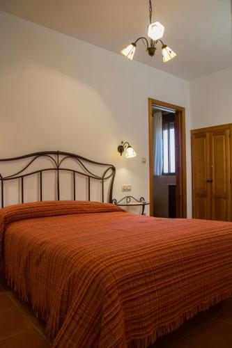 a bedroom with a bed with a orange bedspread at APARTAMENTOS Y HABITACIONES RURALES "El Corral" in Cañizares