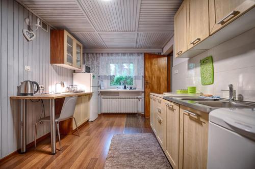 una cocina con armarios de madera, mesa y fregadero en Bagry Rooms, en Cracovia