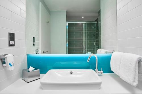 a white and blue bathroom with a sink and a shower at Holiday Inn Express Amsterdam - North Riverside by IHG in Amsterdam