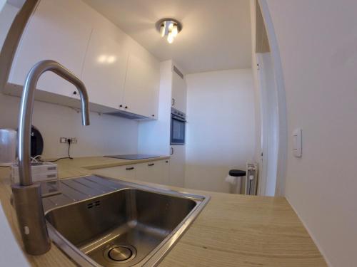 kuchnia ze zlewem ze stali nierdzewnej i łukiem w obiekcie Rustig appartement met zeezicht dicht bij het centrum w Ostendzie