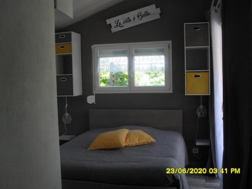 a bed with a yellow pillow in a bedroom at maisonnette neuve à la campagne in Urgosse