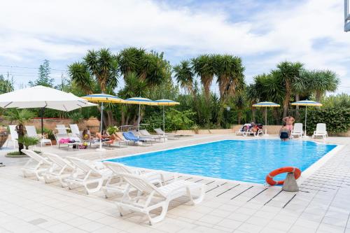 a swimming pool with chairs and umbrellas and people sitting around it at Camping Villaggio Calanovella in Piraino