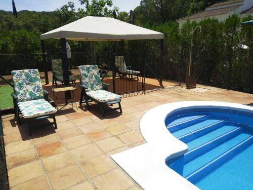 eine Terrasse mit 2 Stühlen und einem Sonnenschirm neben einem Pool in der Unterkunft EL REFUGIO DE POPEA in Santa María de Trassierra