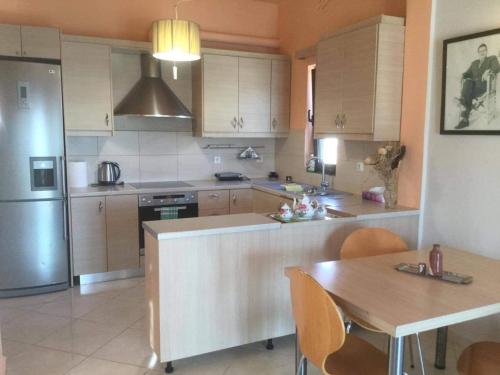 a kitchen with wooden cabinets and a table and a refrigerator at Cosy Country Villa in Pappayiannádhes