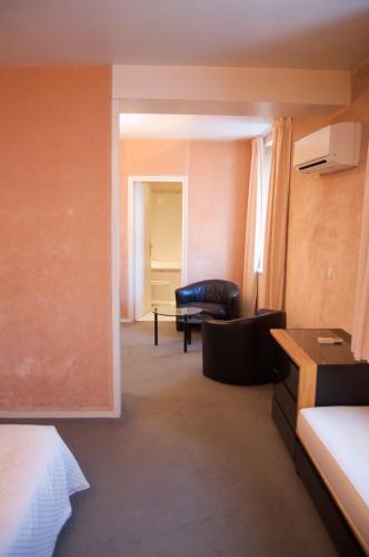 a hotel room with a couch and a chair at Absolue Renaissance in Magny-Cours
