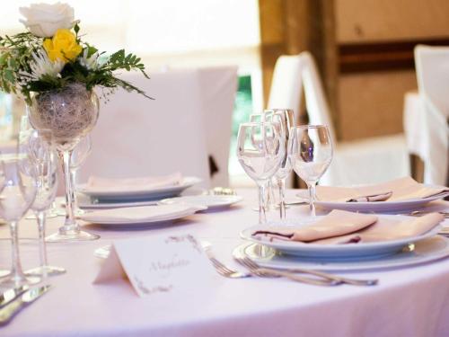 a table with plates and glasses and a vase of flowers at La Vigna Hotel in Bonea