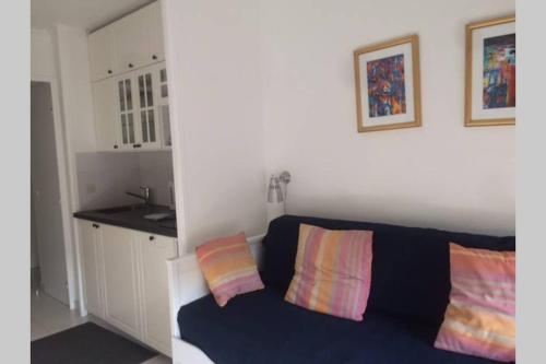 a living room with a black couch with two colorful pillows at La Petite Cachette - Pool and 150m to the beach in Villefranche-sur-Mer