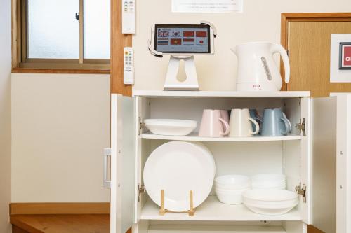 a cupboard with dishes and a scale in a kitchen at Yufu-no-yu Shiki Iyashi in Yufuin