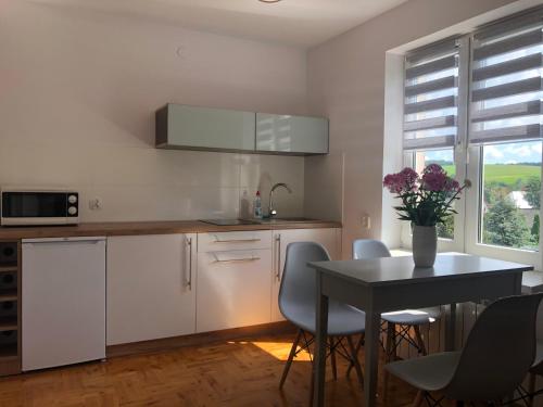 uma cozinha com armários brancos e uma mesa com cadeiras em Apartament Łapacz Snów em Tylicz