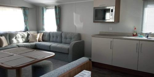 een woonkamer met een bank en een tafel bij Haven Rockley Park,Lytchett Bay View in Hamworthy