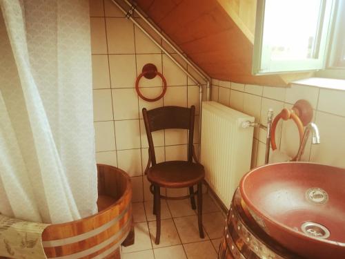 La petite salle de bains est pourvue d'une chaise et d'un lavabo. dans l'établissement Kádárok Vendégháza a Somló-hegyen, à Somlószőlős