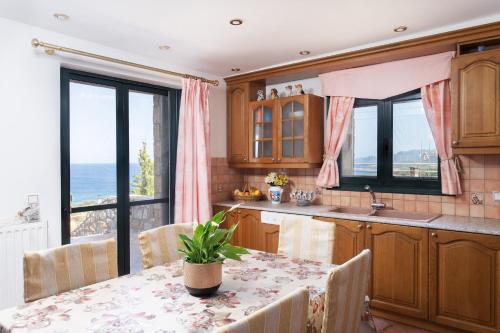 a kitchen with a table with chairs and a view of the ocean at VILLA AVLOS in Monemvasia