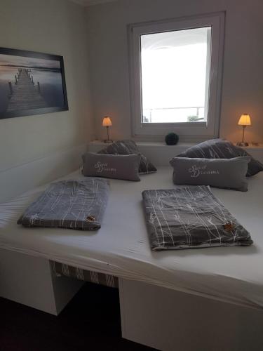 a bed with three pillows on it with a window at Meerblickappartement mit Ladesäule in Glücksburg