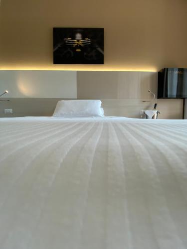 a bedroom with a white bed with a tv on the wall at Hotel Ristorante Novara Expo in Bareggio