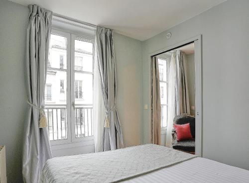 a bedroom with a bed and a mirror and a window at Apartments Du Louvre St Honoré in Paris