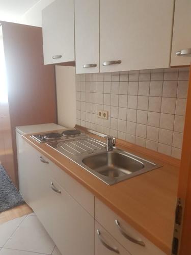a kitchen with a stainless steel sink and white cabinets at Gästehaus-zum-See in Bad Buchau