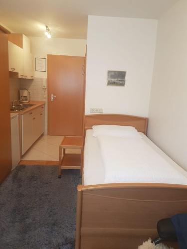 a small bedroom with a bed and a kitchen at Gästehaus-zum-See in Bad Buchau