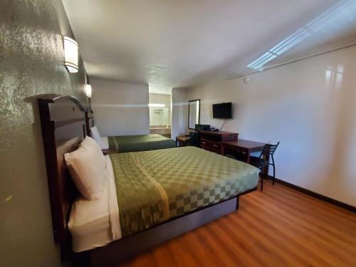 a hotel room with a bed and a desk with a computer at Welcome Inn in Dallas