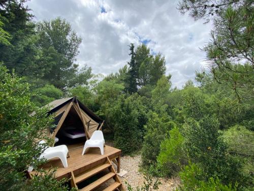 a tent with two white chairs on a wooden deck at Lodge en Pays Cathare in Tuchan
