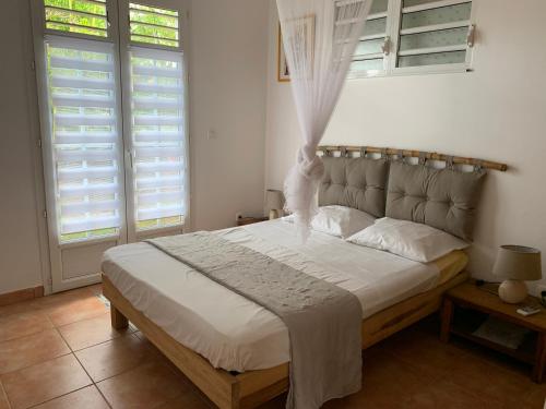 a bedroom with a bed and two windows with shutters at Villa Bois d'Inde in Le Diamant