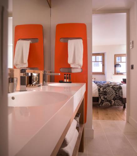 a bathroom with a white sink and orange mirrors at Les Loges Annecy Vieille Ville in Annecy
