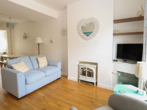 a living room with a blue couch and a fireplace at Gull's Nest in Lowestoft