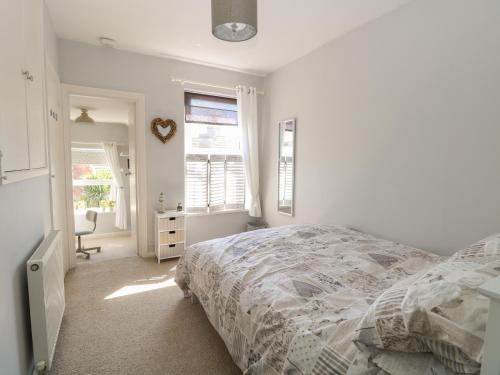 a white bedroom with a bed and a window at Gull's Nest in Lowestoft