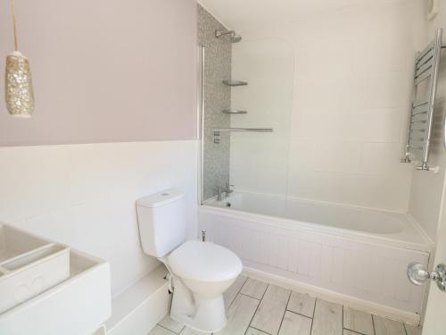a white bathroom with a toilet and a bath tub at Gull's Nest in Lowestoft