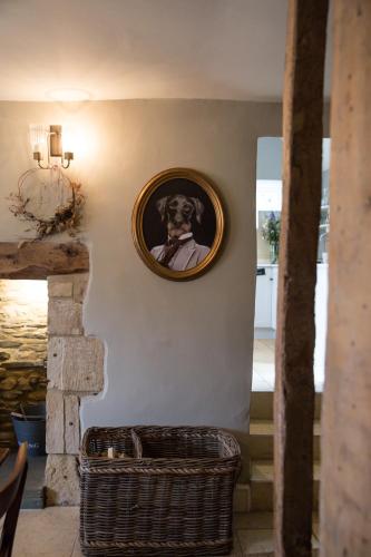 a picture of a dog on a wall with a basket at Jasmine Cottage, Upper Slaughter, Cotswolds in Cheltenham