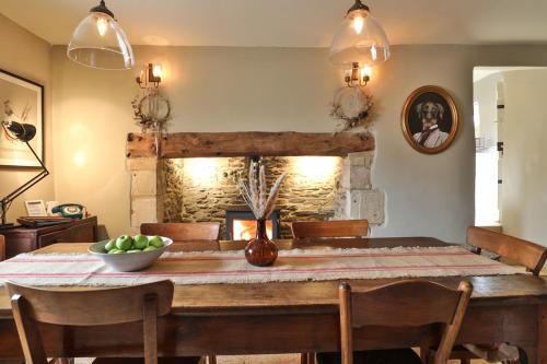 a dining room with a table and a fireplace at Jasmine Cottage, Upper Slaughter, Cotswolds in Cheltenham