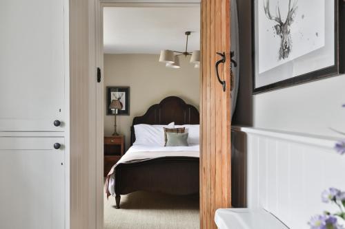 a bedroom with a bed and a mirror at Jasmine Cottage, Upper Slaughter, Cotswolds in Cheltenham