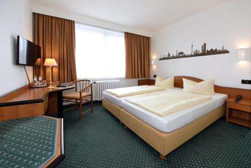 a hotel room with a large bed and a desk at LAT Hotel & Apartmenthaus Berlin in Eisenhüttenstadt