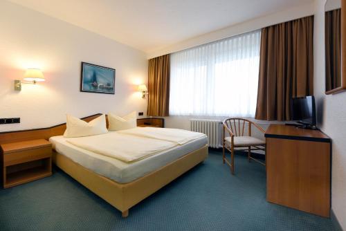 a hotel room with a bed and a chair at LAT Hotel & Apartmenthaus Berlin in Eisenhüttenstadt