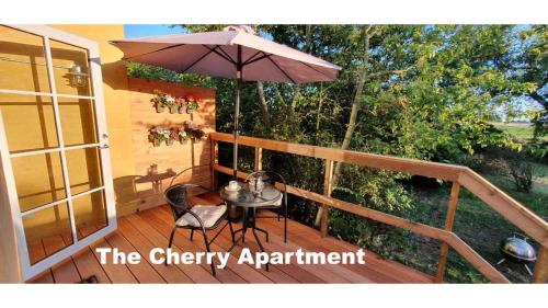 The Cherry Apartment - 'Den Gule Svane' Guest House near Rønne & Beach في رونيه: فناء فيه مظلة وطاولة وكراسي