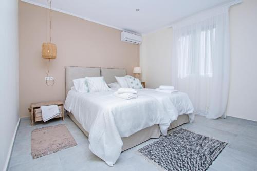 a white bedroom with a large bed with white sheets at Athena Luxury Apartments in Mesongi