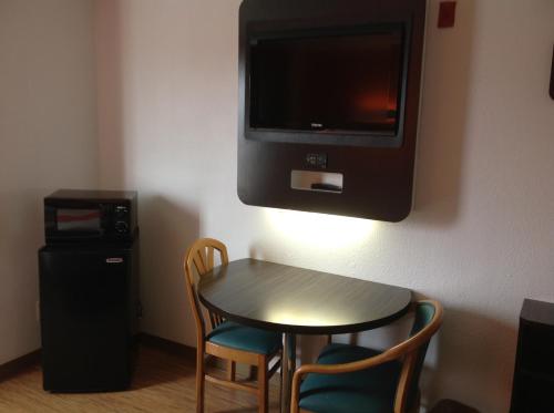 a small table with chairs and a television on a wall at Motel 6-Dallas, TX - Northeast in Garland