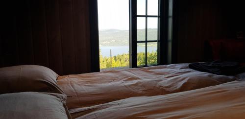 a bed in a room with a large window at Mjøshytte in Stange