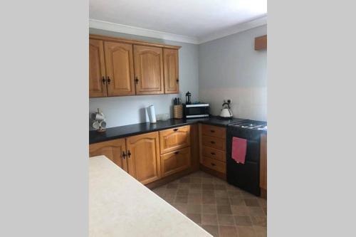 a kitchen with wooden cabinets and a black appliances at Luí na Gréine in Gweedore